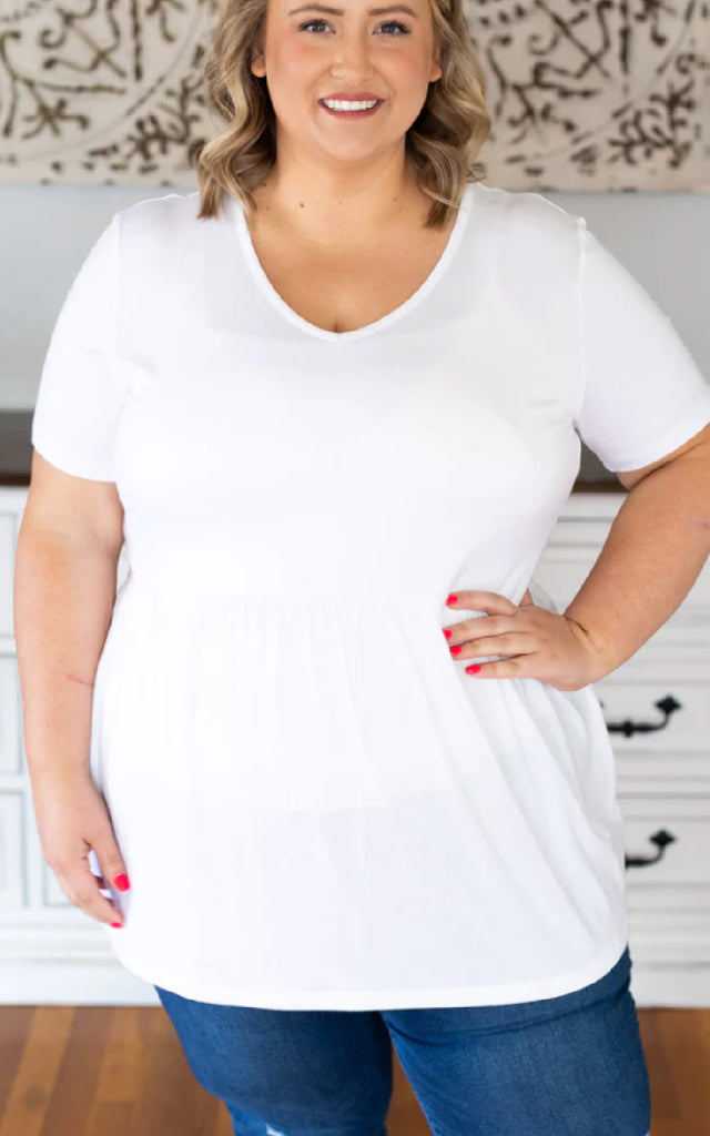 Woman wearing a white babydoll short sleeve top. 