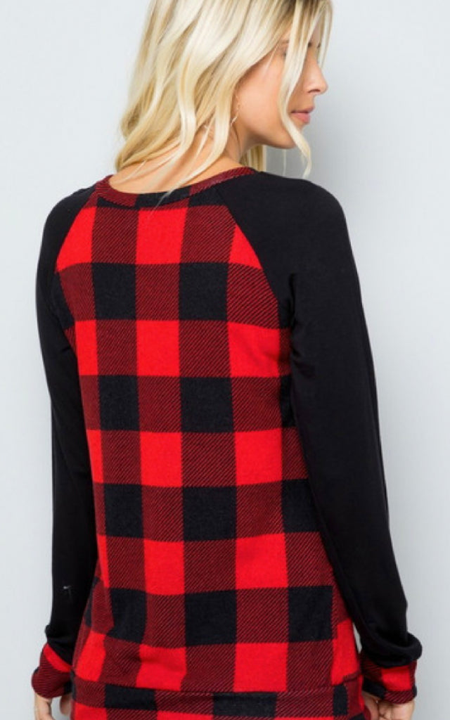 Woman wearing a raglan style shirt in a buffalo plaid print.